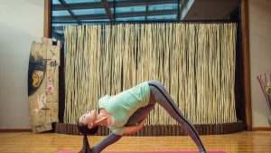 woman in green tank top and gray leggings doing yoga